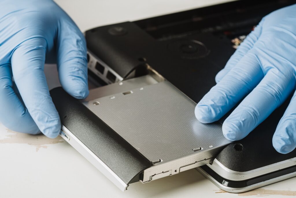 Hands pulling a dvd drive out of an old laptop